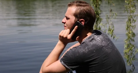 Happy Young Man Talking on Mobile Phone Positive Dialogue near Water Park Lake Video stock 87942991