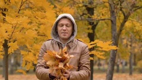 Happy young man throws maple leaves over his head Stock Footage 120091942