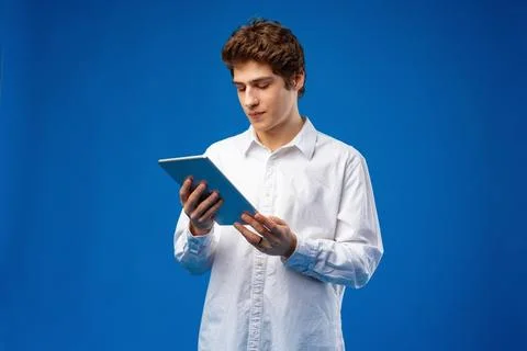 Happy young man using digital tablet on blue background. Stock Photos