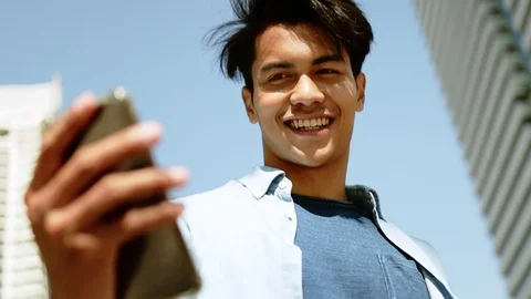 A Happy Young Man Using Mobile Phone in Urban City. Orbit Shot. Slow Motion. 库存影片 123148864