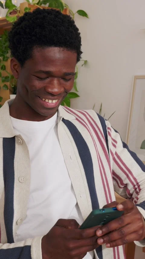 Happy young man using mobile phone while sitting at home office workplace Stock Footage 312202522