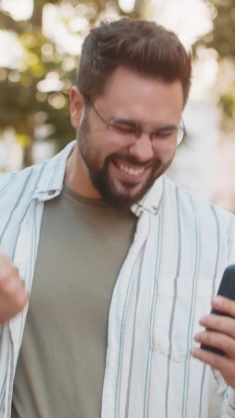 Happy young man using smartphone celebrating victory win good message news on Stock Footage 323332086