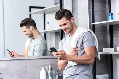 Happy young man using smartphone in bathroom Fotos Stock