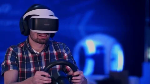 Happy young man in virtual reality headset playing videogame with racing wheel Stock Footage 74390163