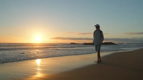 Happy young man walking on a sandy ocean beach on a sunny summer day, in sl.. Stock Footage 253272564