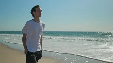 Happy young man walking on a sandy beach against background of the ocean on.. Stock Footage 302920903