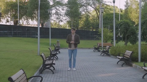 A happy young man walks down the street and sincerely feels excited to learn Video stock 77375513