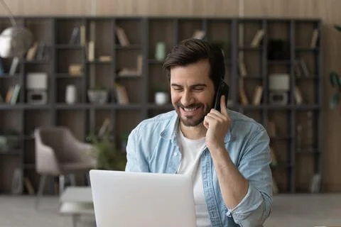 Happy young man working on computer, discussing distantly with colleagues. Stock-Fotos