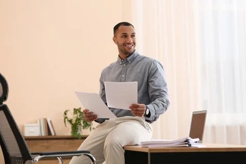 Happy young man working with documents on wooden table in office Stock Photos