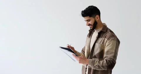 Happy young man writing on notepad Stock Footage 196078609