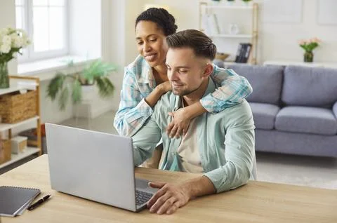 Happy young mixed race using laptop computer for remote work at home office Stockfoto's