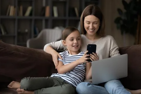 Happy young mother and little daughter use gadgets Stock Photos