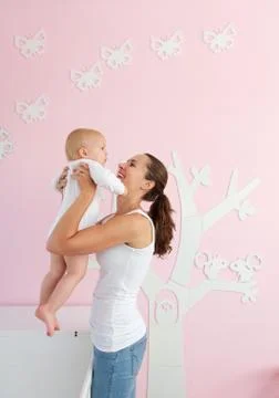 Happy young mother lifting baby from crib at home Foto stock