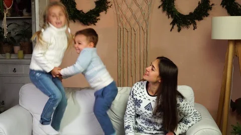 Happy young mother looking at excited kids in Christmas atmosphere room holding Stock Footage 98661853