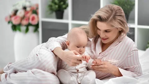 Happy young mother playing with cute little son lying on bed together. Shot with Stock-Footage 137463517