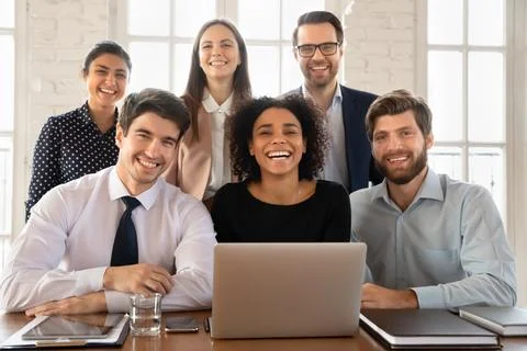 Happy young multiethnic team posing at workplace table Stock Photos