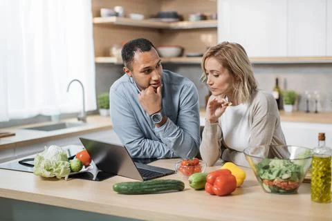 Happy young multiracial couple using laptop computer preparing healthy food diet Foto stock