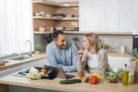 Happy young multiracial couple using laptop computer preparing healthy food diet Foto stock