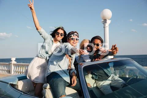 Happy young people driving car near the sea Stock Photos