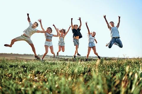 Happy young people jumping in mountains at sunny day. Stock Photos