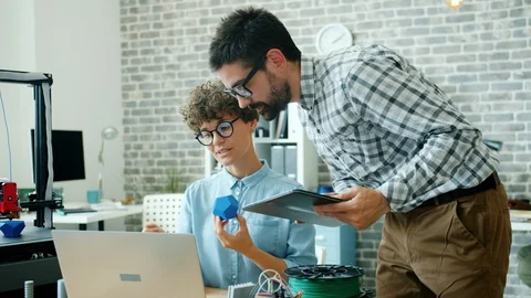 Happy young people making 3d printed model talking using tablet in office Stock Footage 119765952