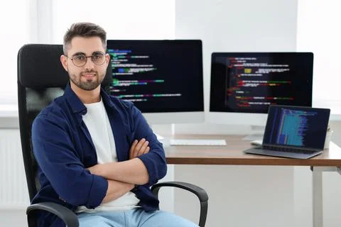 Happy young programmer working at desk in office Foto stock