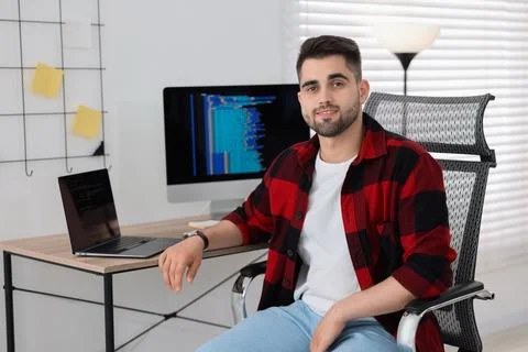 Happy young programmer working at desk in office Foto stock