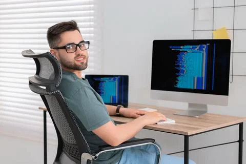 Happy young programmer working at desk in office 写真素材