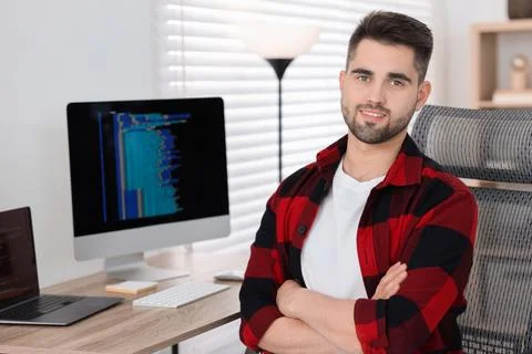 Happy young programmer working at desk in office Stock Photos