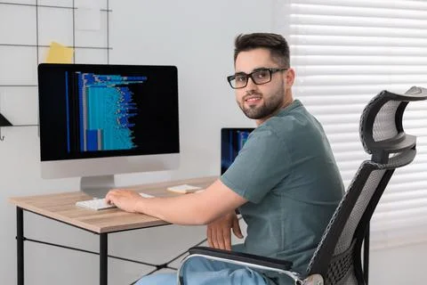 Happy young programmer working at desk in office 스톡 사진