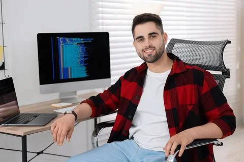 Happy young programmer working at desk in office Foto stock