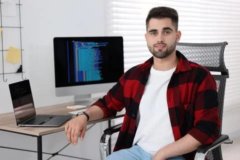 Happy young programmer working at desk in office Foto stock