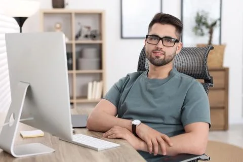 Happy young programmer working with at desk in office 写真素材