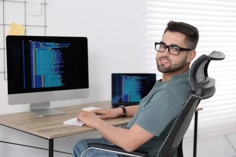 Happy young programmer working at desk in office Stock Photos