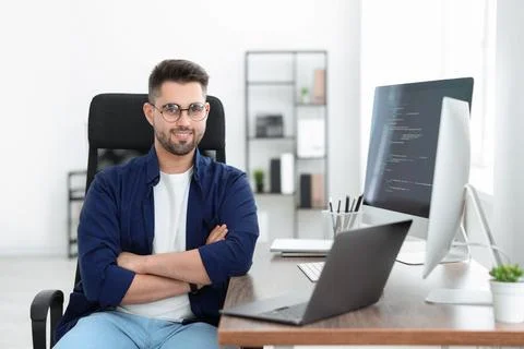 Happy young programmer working with laptop in office Stock Photos