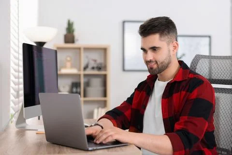 Happy young programmer working with laptop in office 库存照片