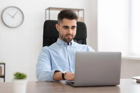 Happy young programmer working with laptop in office 스톡 사진