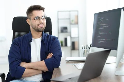 Happy young programmer working with laptop in office 库存照片