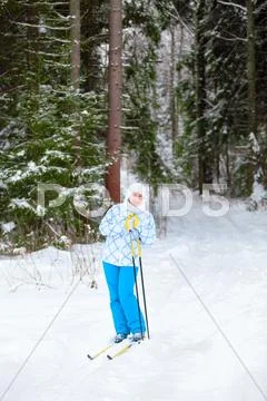 Happy young skier with ski poles in hands up in winter forest Stock Photos