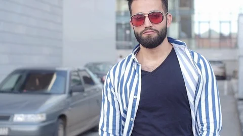 Happy young smiling stylish guy in sunglasses on a city street Stock Footage 113501661