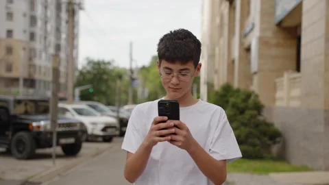 Happy young student checking smartphone and celebrating success outdoors Stock Footage 333640975