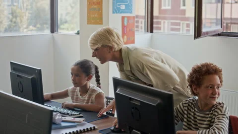 Happy Young Teacher of Programming School Helping Schoolchildren at Lesson Stock Footage 316479957
