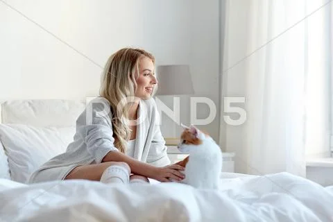 Happy young woman with cat in bed at home Stock Photos