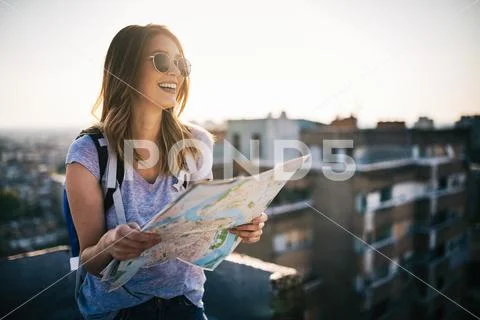 Happy young woman with a city map and a backpack travelling Stock Photos