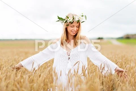 Happy young woman in flower wreath on cereal field Stock Photos