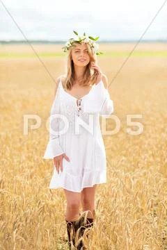 Happy young woman in flower wreath on cereal field Stock Photos