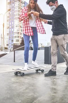 Happy young woman learning with her instructor at the skateboarding ramp. Summer Stock Photos