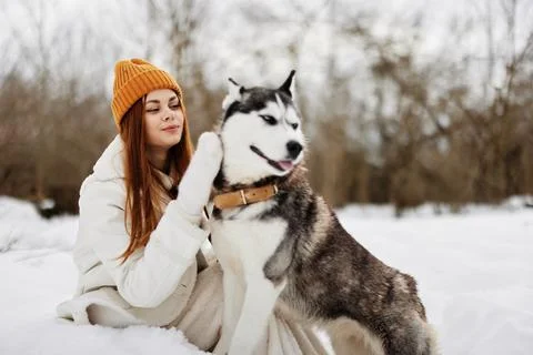 Happy young woman outdoors in a field in winter walking with a dog fresh air Stock Photos
