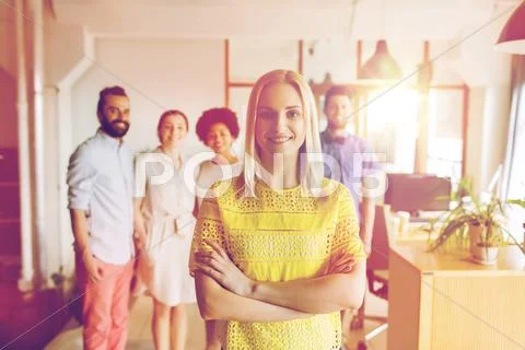 Happy young woman over creative team in office Stock Photos