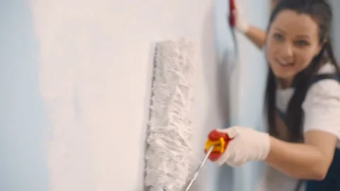 Happy young woman painting interior wall with paint roller in new house Stock Footage